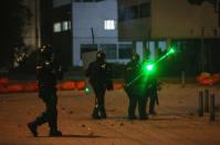 Demonstrators shine lasers at riot police during a protest at the National University as a national strike continues in Bogota