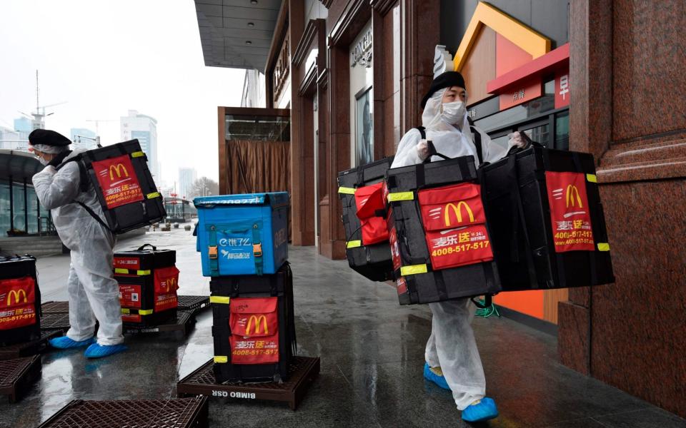 McDonalds workers wear protective suits as a preventive measure against the COVID-19 coronavirus as they prepare to deliver food to residents in Wuhan, in China - STR / AFP