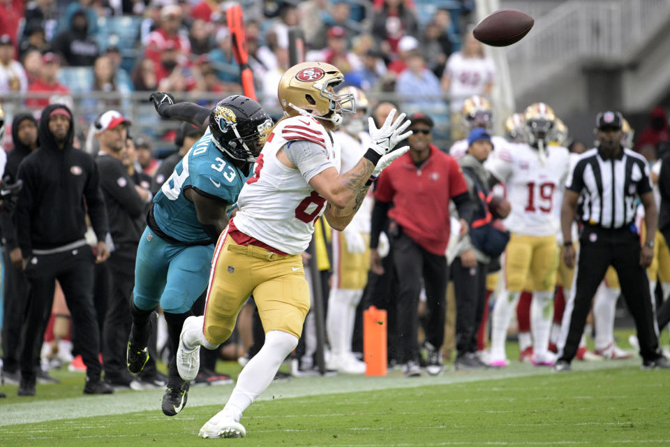 San Francisco 49ers tight end George Kittle, right, makes a catch to run for a touchdown as Jacksonville Jaguars linebacker Devin Lloyd (33) defends during the second half of an NFL football game, Sunday, Nov. 12, 2023, in Jacksonville, Fla. (AP Photo/Phelan M. Ebenhack)