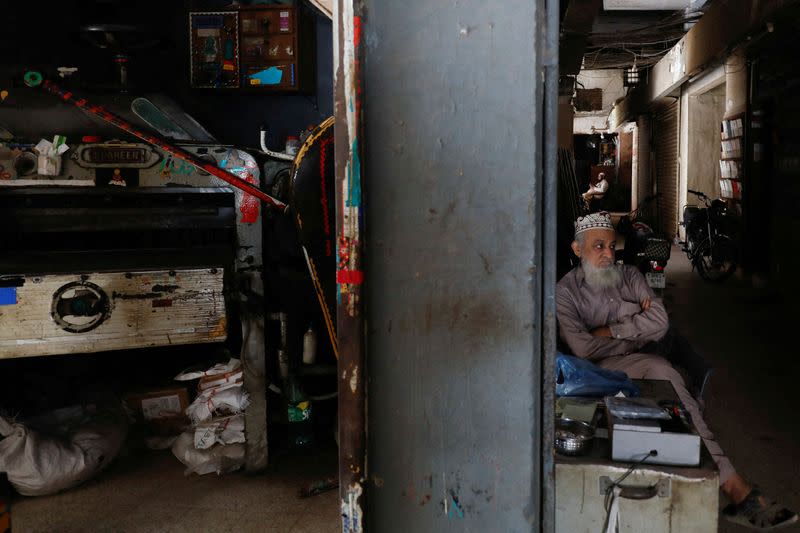 FILE PHOTO: A man sits outside his shop during a country-wide power breakdown in Karachi