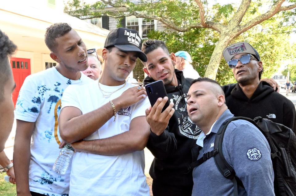 EDGARTOWN   9/15/22   Venezuelan immigrants use their phone for entertainment outside  St. Andrews Episcopal Church in Edgartown Thursday