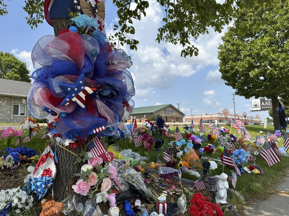 Flowers and flags are placed at the memorial for fallen Fargo Police Officer Jake Wallin in Fargo, N.D., on Friday, July 21, 2023. The man who shot three Fargo police officers and a civilian, killing one of the officers before an officer killed him, searched the internet for terms including “explosive ammo” and “kill fast,” as well as for what crowded area events might be happening in and around North Dakota's largest city, authorities said Friday. (AP Photo/Jack Dura)