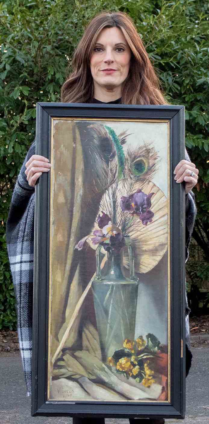 A woman holds up a painting