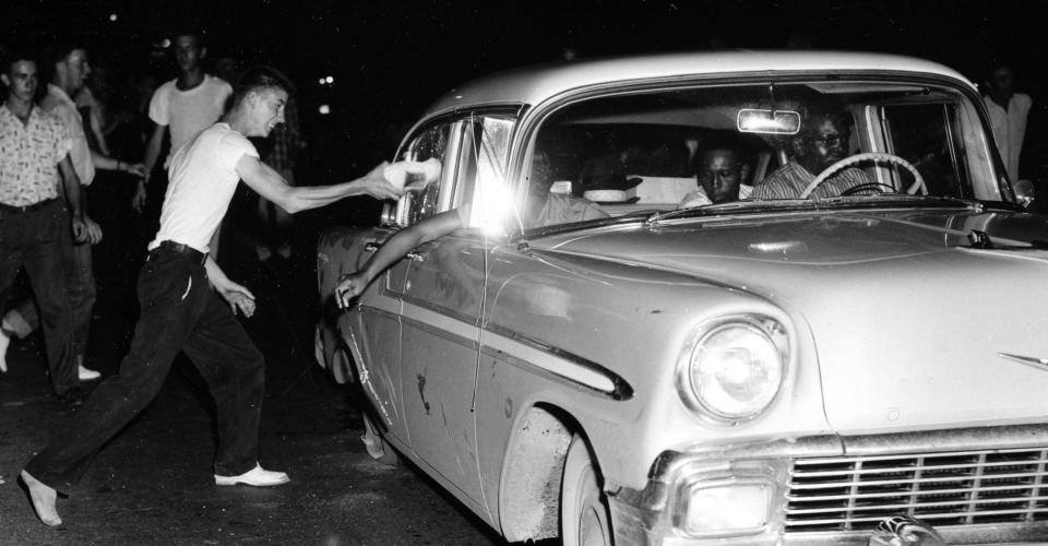 A youth uses his shoe to damage an out-of-state car with a flat rear tire carrying black Americans in Clinton, Tenn., Aug. 31, 1956. The car was one of six carrying Black occupants that were attacked by an angry mob. AP Photo/Gene Herrick