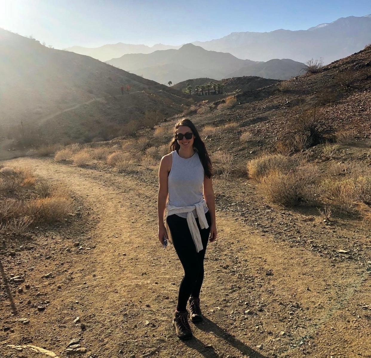 A woman on a hike in a desert landscape at golden hour.