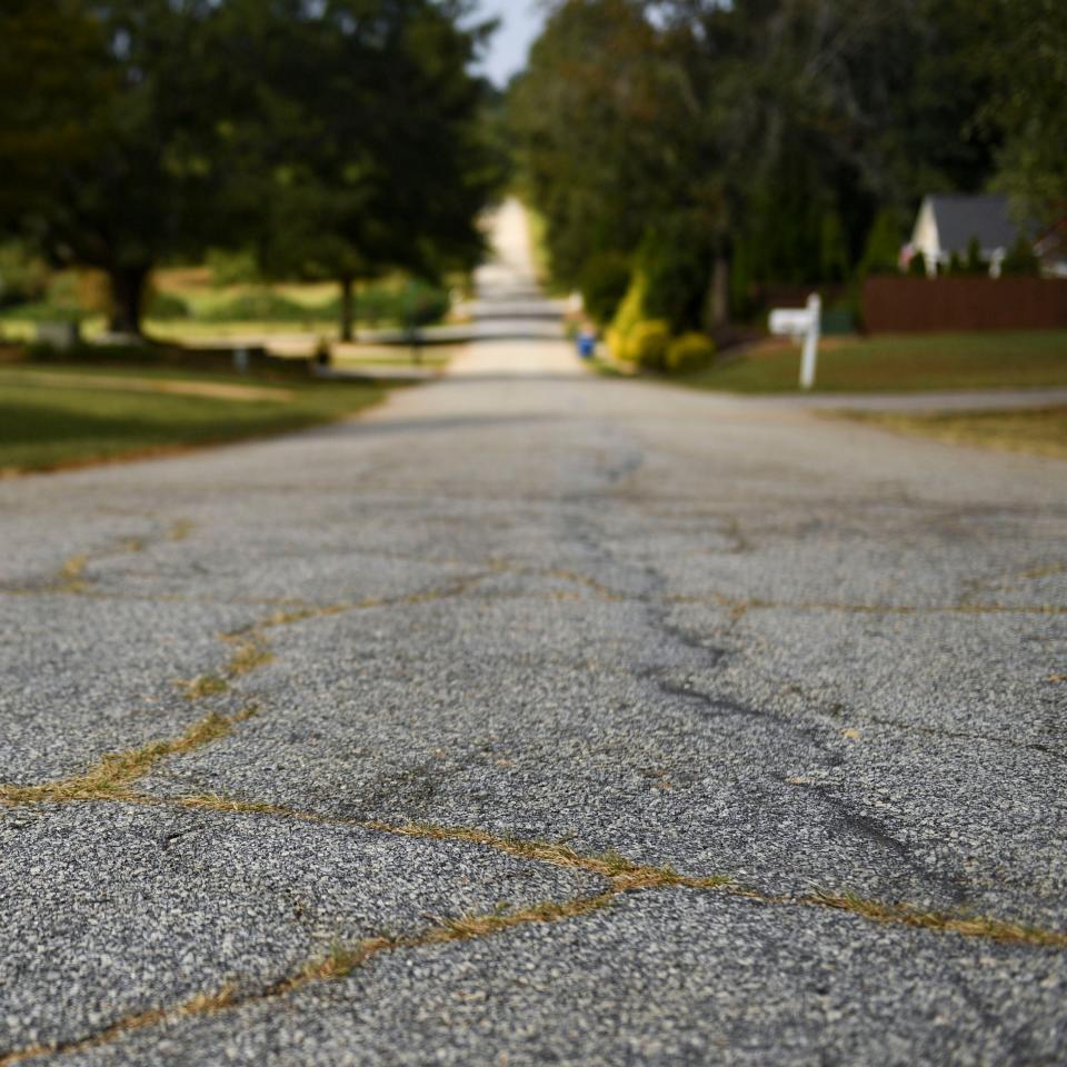 Grass is seen growing through cracks in the pavement in the cul de sac on Hawkins Creek Court in Greenville, S.C., on Wednesday, Oct. 4. Hawkins Creek Court, beginning at Old Bucombe Road, is on Greenville County's most recent paving list.