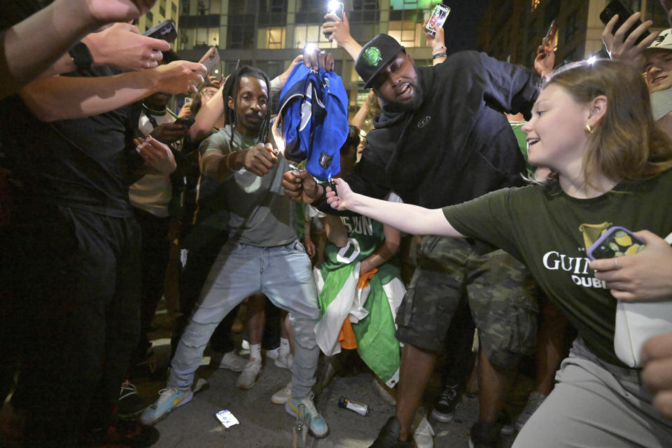 Boston Celtics fans attempt to light a Dallas Mavericks jersey on fire outside the TD Garden following the Celtics victory over the Mavericks in Game 5 of the NBA basketball finals in Boston, Monday, June 17, 2024. (AP Photo/Josh Reynolds)