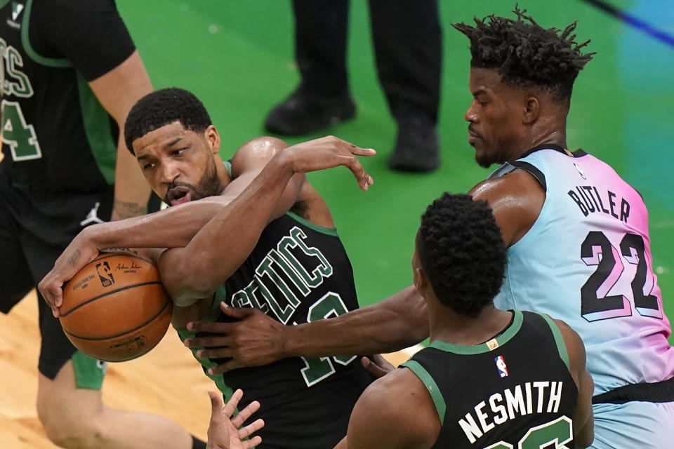 Boston Celtics' Tristan Thompson, left, grips the ball under pressure from Miami Heat's Jimmy Butler, right, as Celtics' Aaron Nesmith, center, looks on in the first half of a basketball game, Sunday, May 9, 2021, in Boston. (AP Photo/Steven Senne)