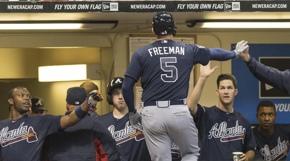 Freddie Freeman, de los Bravos de Atlanta, vuelve al dugout, felicitado por sus compañeros, luego de conectar un jonrón frente a Zach Duke, de los Cerveceros de Milwaukee, en el juego del martes 1 de abril de 2014 (AP Foto/Tom Lynn)