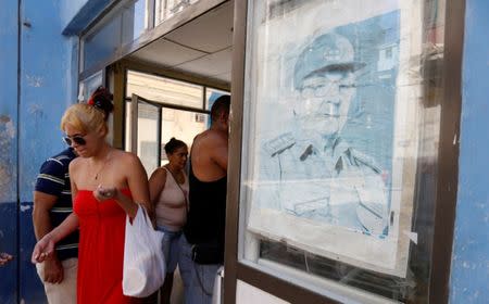 A picture of the former Cuban President Raul Castro is seen as a woman comes out of the local shop in Havana, Cuba July 21, 2018. REUTERS/Stringer