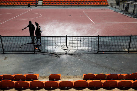 People stand in a sports ground damaged by a rocket fired from the Gaza Strip, in Netivot, Israel, May 30, 2018. REUTERS/ Amir Cohen