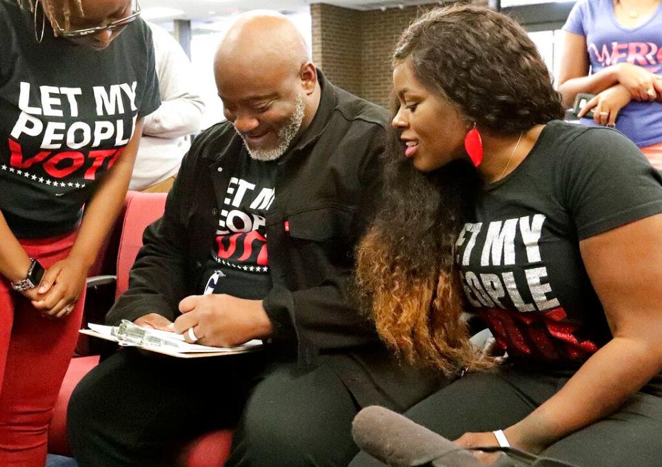 In this Jan. 8, 2019 photo, former felon Desmond Meade and president of the Florida Rights Restoration Coalition, left, fills out a voter registration form as his wife Sheena looks on at the Supervisor of Elections office in Orlando.