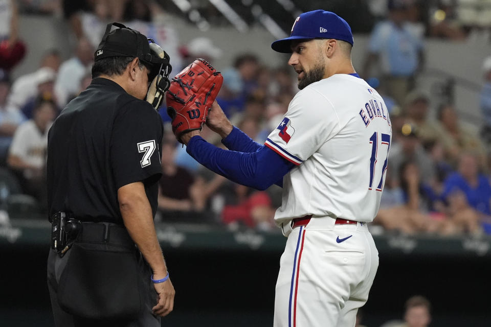 Texas Rangers starting pitcher Nathan Eovaldi (17) asks for a clarification of a call by home plate umpire Alfonso Marquez (72) during the seventh inning of a baseball game against the San Diego Padres in Arlington, Texas, Tuesday, July 2, 2024. (AP Photo/LM Otero)