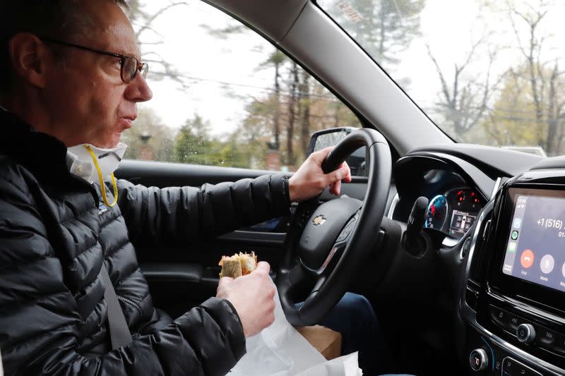 Dr Greg Gulbransen eats a sandwich while driving to a house call and talking to a Bank of America Small Business Loan representative as he maintains visits with both his regular patients and those confirmed to have the coronavirus disease (COVID-19) in Oys