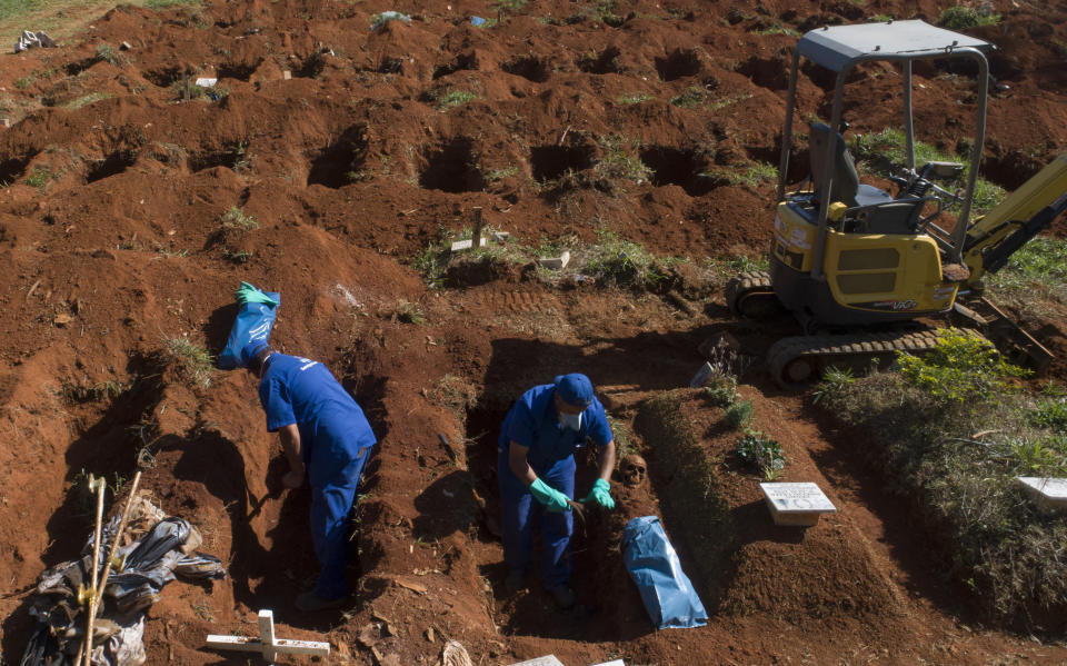 Operarios retiran los restos de personas sepultadas hace tres años en el cementerio de Vila Formosa, que no cobra a las familias por las tumbas, en Sao Paulo, Brasil, el 12 de junio de 2020. Los cuerpos sepultados hace al menos tres años, se exhuman y almacenan en bolsas de plástico para dejar sitio a más féretros, una necesidad más acuciante en la pandemia del coronavirus. (AP Foto/Andre Penner)