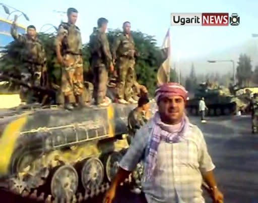 An image grab from a video uploaded on YouTube shows what anti-regime protesters claim to be defected soldiers standing on tanks amid demonstrators in the city of Hama. Note: AFP is not authorized to cover this event and is therefore using pictures from alternative sources, which cannot be independently verified