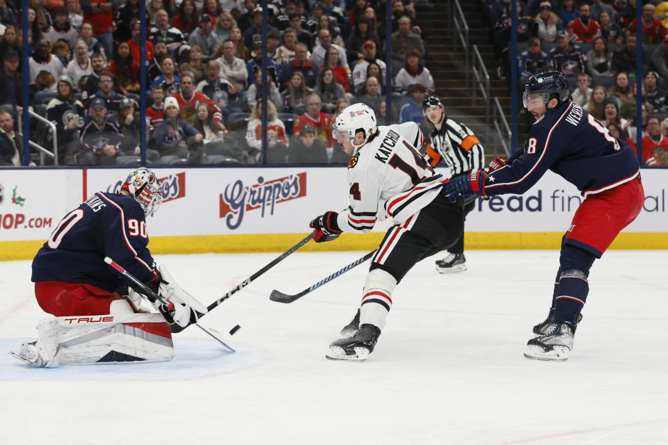 Columbus Blue Jackets' Elvis Merzlikins, left, makes a save against Chicago Blackhawks' Boris Katchouk, center, as Blue Jackets' Zach Werenski defends during the first period of an NHL hockey game Wednesday, Nov. 22, 2023, in Columbus, Ohio. (AP Photo/Jay LaPrete)