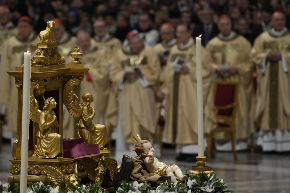 A statue of Baby Jesus is backdropped by cardinals as Pope Francis presides over Christmas eve Mass, at St. Peter's Basilica at the Vatican, Sunday Dec. 24, 2023. (AP Photo/Gregorio Borgia)