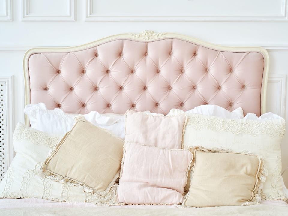 Pink headboard with diamond tufting on bed with white, yellow, and pink pillows