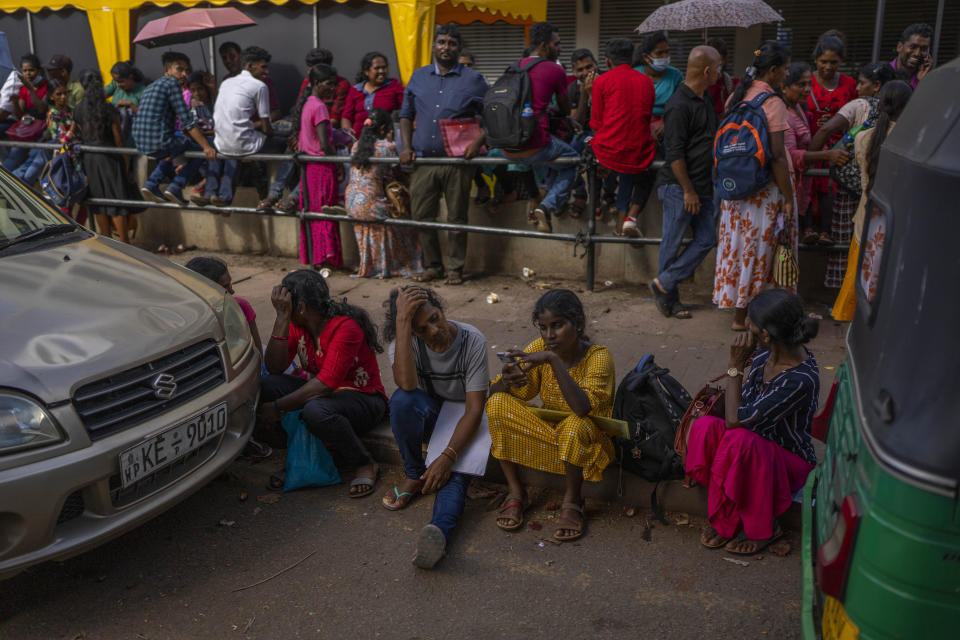 People wait in queue to get their passports outside Department of Immigration & Emigration in Colombo, Sri Lanka, Monday, July 18, 2022. Bankruptcy has forced the island nation's government to a near standstill. Parliament is expected to elect a new leader Wednesday, paving the way for a fresh government, but it is unclear if that's enough to fix a shattered economy and placate a furious nation of 22 million that has grown disillusioned with politicians of all stripes. (AP Photo/Rafiq Maqbool)