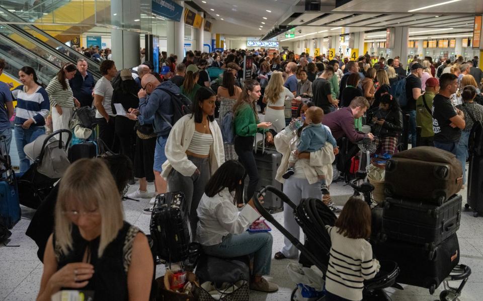 People wait near check-in desks at Gatwick Airport
