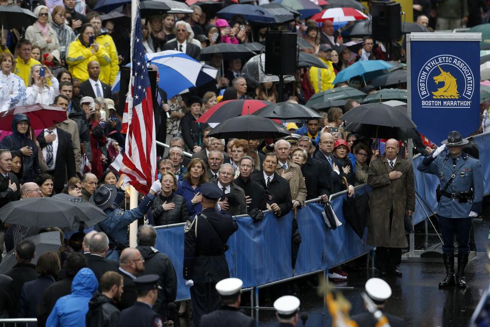 Dignitaries, survivors and first responders watch as a flag is raised near the site of one of the two bomb blasts on the one-year anniversary of the 2013 Boston Marathon bombings in Boston, Massachusetts, April 15, 2014. U.S. Vice President Joe Biden, other leaders and survivors of the Boston Marathon bombing shared messages of thanks and defiance on Tuesday at a tribute to the three people killed and 264 wounded in the attack exactly one year ago. REUTERS/Dominick Reuter (UNITED STATES - Tags: SPORT ATHLETICS DISASTER CRIME LAW ANNIVERSARY)