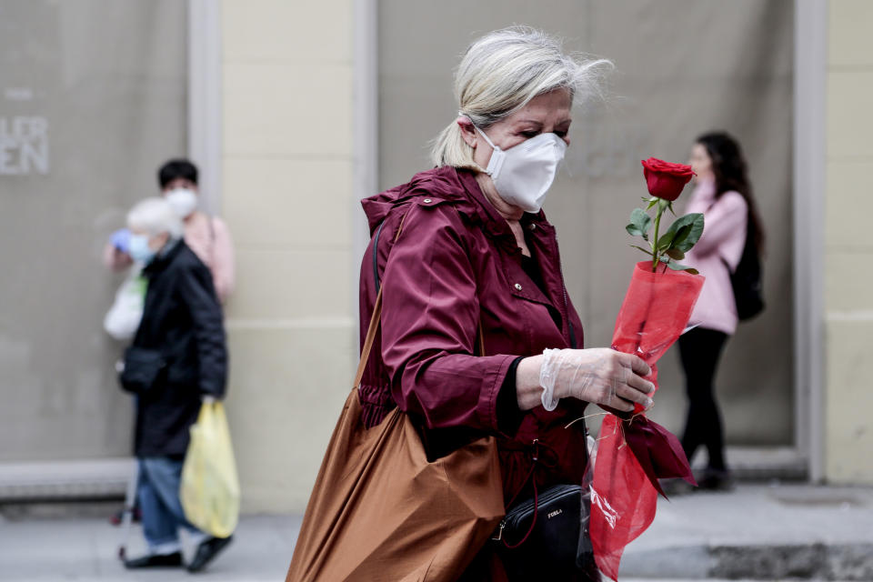 BARCELONA, SPAIN - APRIL 23:  A woman is seen wearing a face mask and caring a Sant Jordi's rose during Sant Jordi, Saint George's Day on April 23, 2020 in Barcelona, Spain. Catalans are celebrating Sant Jordi at home under strict lockdown measures which are restricting them from leaving home to buy the traditional red rose and book to be given as presents to their loved ones. Last year more than 7 million roses were sold for this day. (Photo by Miquel Benitez/Getty Images)