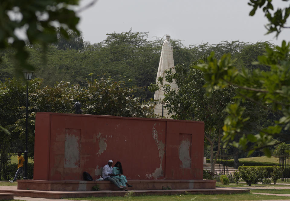 A couple sits near a statue of King George V in coronation park, which houses statues of old British Kings and rulers in New Delhi, Sunday, Sept. 11, 2022. India, once the largest of Britain’s colonies that endured two centuries of imperial rule has moved on. Queen Elizabeth II’s death provoked sympathies from some while for a few others, it jogged memories of a bloody history under the British crown. Among most regular Indians, the news was met with an indifferent shrug. (AP Photo/Manish Swarup)