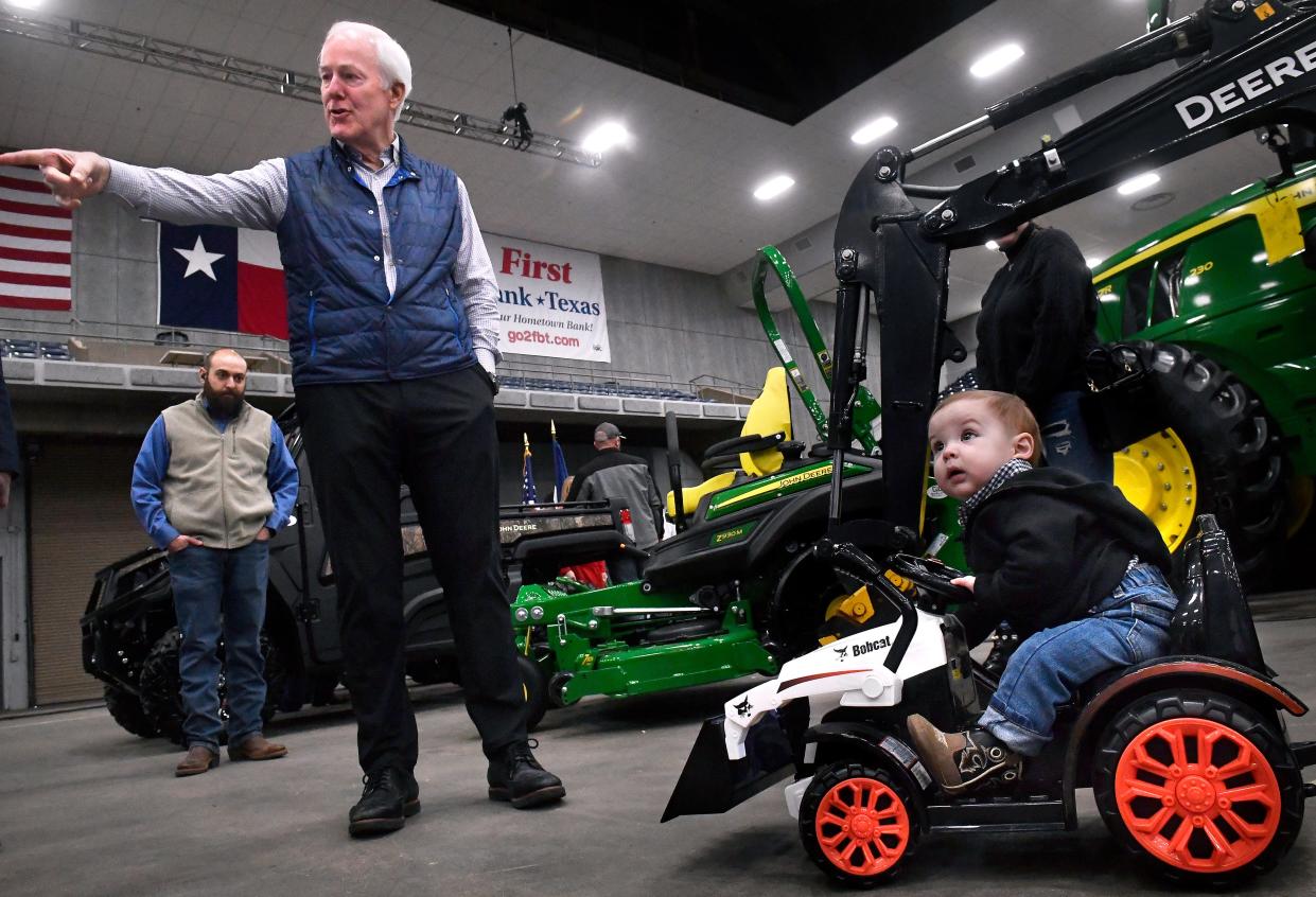U.S. Sen. John Cornyn pauses beside 11-month-old Everett Young in his tour of the Texas Farm Ranch Wildlife Expo on Tuesday. Everett rode on a pint-sized tractor controlled by his grandfather Chris Ellis with Bobcat of Abilene.