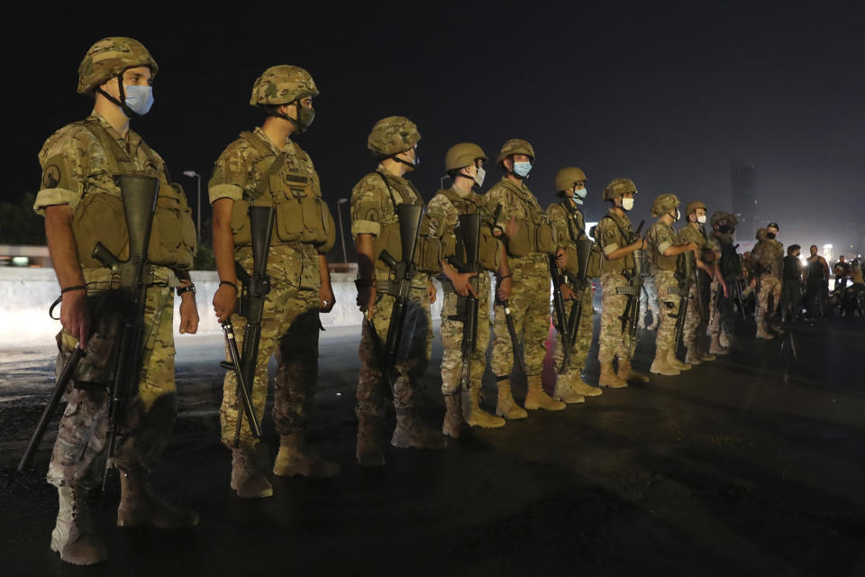 Lebanese army soldiers stand guard as anti-government protesters block a main highway during a demonstration against deteriorating economic conditions as politicians are deadlocked over forming a new government, in the town of Jal el-Dib, north of Beirut, Lebanon, Sunday, Sept. 27, 2020. Lebanese Prime Minister-designate Mustapha Adib resigned Saturday amid a political impasse over government formation, dealing a blow to French President Emmanuel Macron's efforts to break a dangerous stalemate in the crisis-hit country. (AP Photo/Bilal Hussein)