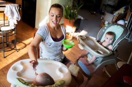 Heather Padgett feeds her daughters Kinsley and Kiley at her home in Cincinnati, Ohio July 16, 2015. REUTERS/Aaron P. Bernstein