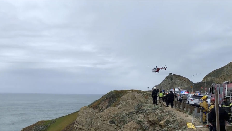 In this image from video provided by Cal Fire San Mateo, Santa Cruz Unit, emergency personnel respond to the scene after a Tesla plunged off a cliff along the Pacific Coast Highway, Monday, Jan. 2, 2023, in Northern California, near an area known as Devil's Slide, leaving four people in critical condition, a fire official said. The vehicle fell about 250 feet (76.20 meters) from the highway, the fire official said. Motorists were told to expect delays as rescuers worked. Helicopters were expected to transport four people to hospitals. (Cal Fire San Mateo - Santa Cruz Unit via AP)