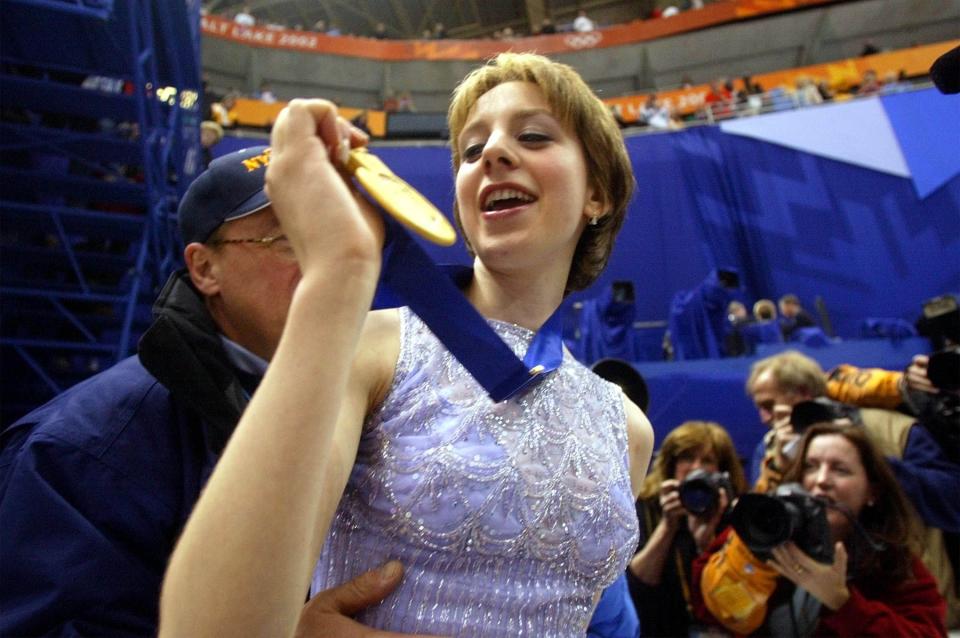 Sarah Hughes of the U.S. looks at her gold medal after kissing her dad, John, while her mom, Amy, looks on after winning the gold medal after her free program on Thursday, Feb 21, 2002, at the Salt Lake Ice Center. | Chuck Wing, Deseret News