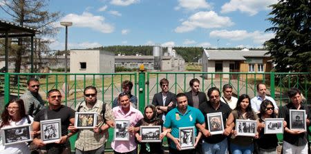 FILE PHOTO: Participants of the European Meeting of Antiracist Leaders hold pictures in front of a pig farm, situated at the site of a former Roma concentration camp, to commemorate victims of the Holocaust during World War Two in the village of Lety June 13, 2014. REUTERS/David W Cerny/File Photo