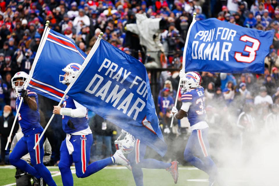 The Buffalo Bills carry flags onto the field displaying the number 3 in support of safety Damar Hamlin before an NFL football game against the New England Patriots, Sunday, Jan. 8, 2023, in Orchard Park, N.Y. Hamlin remains hospitalized after suffering a catastrophic on-field collapse in the team's previous game against the Cincinnati Bengals. (AP Photo/Jeffrey T. Barnes)