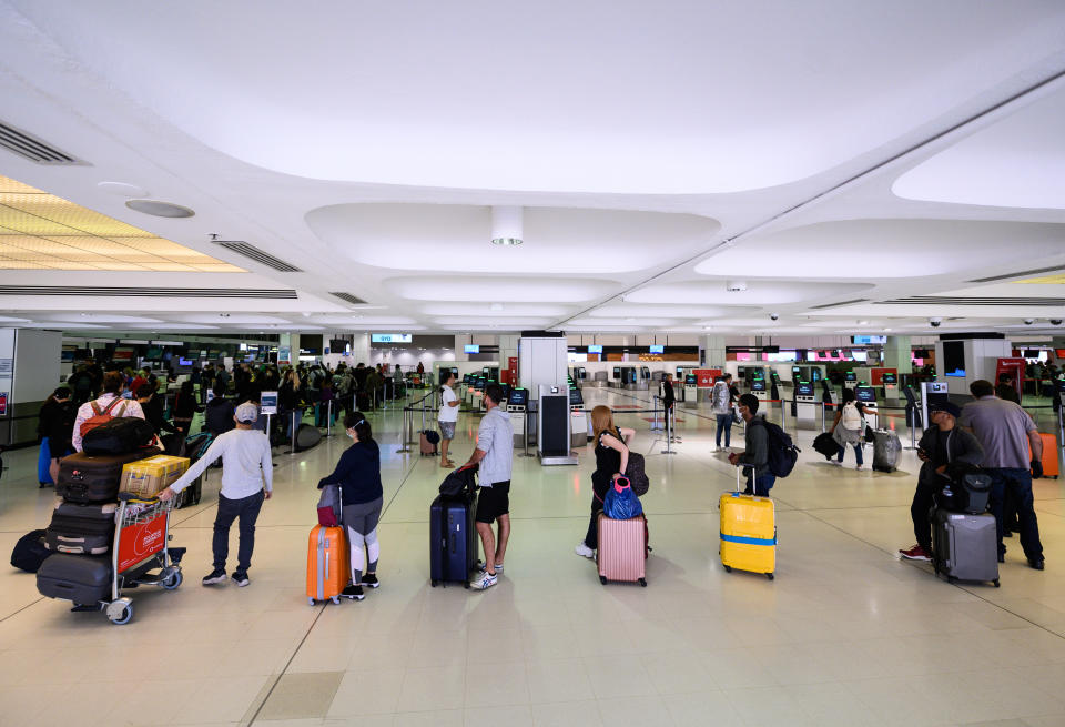 Travellers adhere to social-distancing rules as they check in for their flights at the Sydney International Airport.