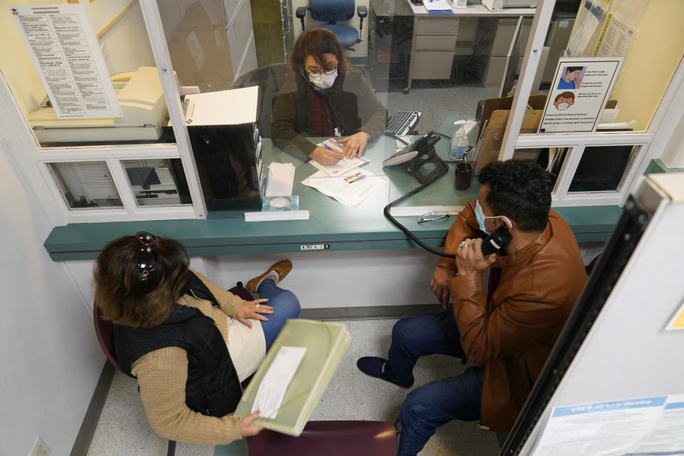 Mohammad Attaie and his wife Deena, newly arrived from Afghanistan, get assistance from medical translator Jahannaz Afshar making a doctor's appointment at the Valley Health Center TB/Refugee Program in San Jose, Calif., on Dec. 9, 2021. The staff of Silicon Valley's decades-old refugee health clinic may not all speak the language of the Afghan refugees starting new lives in the San Francisco Bay Area. But they know the anxiety and stress of newcomers who fled war and chaos to end up in a country where they don't speak the language and everything is different. (AP Photo/Eric Risberg)