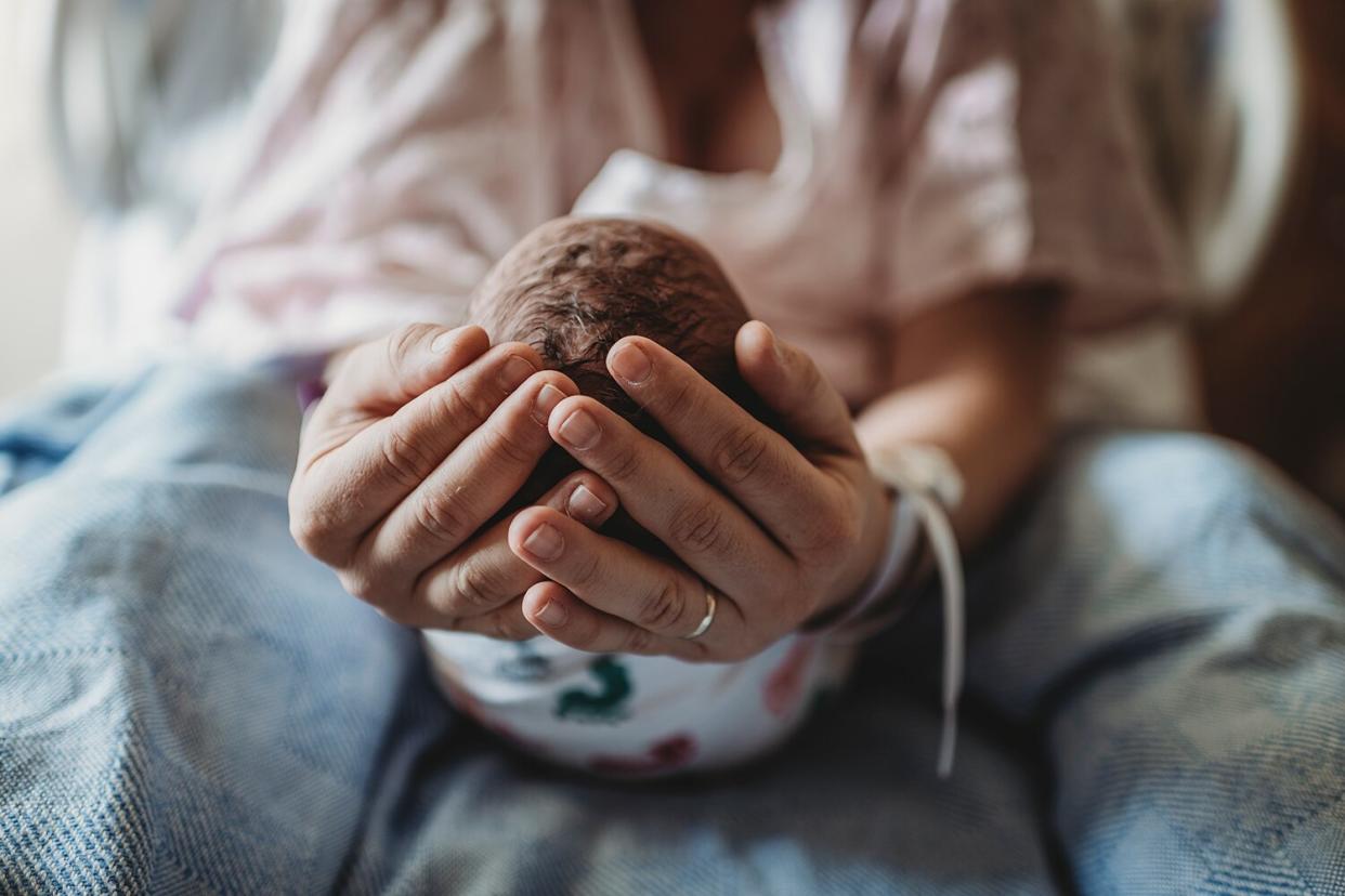 mothers hands holding newborn boy's head