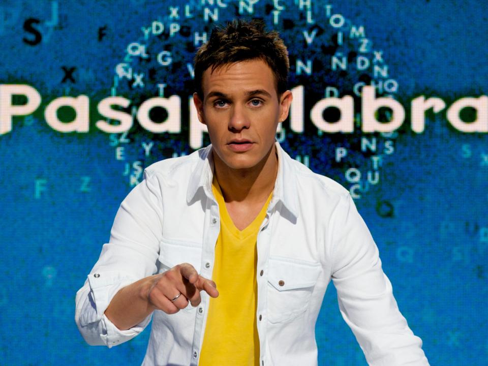 "Pasapalabra" host Christian Galvez wearing white jacket and yellow shirt in front of blue background