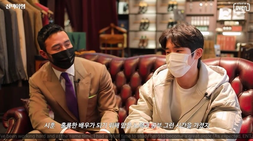 Jin-taek and Si-hun talk on a leather couch at Jin-taek's tailor shop