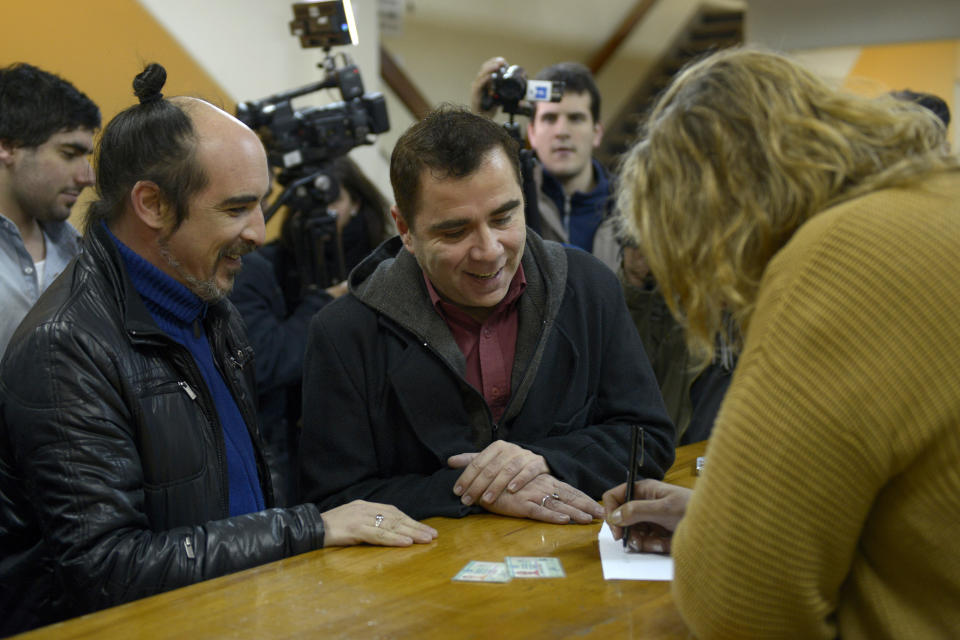 Rodrigo Borda, left, and his partner Sergio Miranda watch a Civil Registry worker take down their information to apply to get married in Montevideo, Uruguay, Monday, Aug. 5, 2013. (AP Photo/Matilde Campodonico)