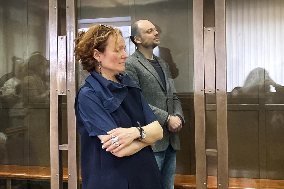 In this handout photo released by the Moscow City Court, Russian opposition activist Vladimir Kara-Murza stands in a class cage and his lawyer, Maria Eismont as they listen to the verdict in a courtroom at the Moscow City Court in Moscow, on Monday April 17, 2023. A top Kremlin foe was convicted Monday on charges of treason and denigrating the Russian military and sentenced him to 25 years in prison after a trial that marked the latest move in a relentless crackdown on the opposition amid the fighting in Ukraine. (The Moscow City Court via AP)