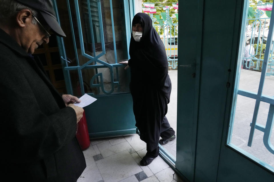 An Iranian woman arrives as a man leaves a polling station during the parliamentary runoff elections in Tehran, Iran, Friday, May 10, 2024. Iranians voted Friday in a runoff election for the remaining seats in the country's parliament after hard-line politicians dominated March balloting. (AP Photo/Vahid Salemi)