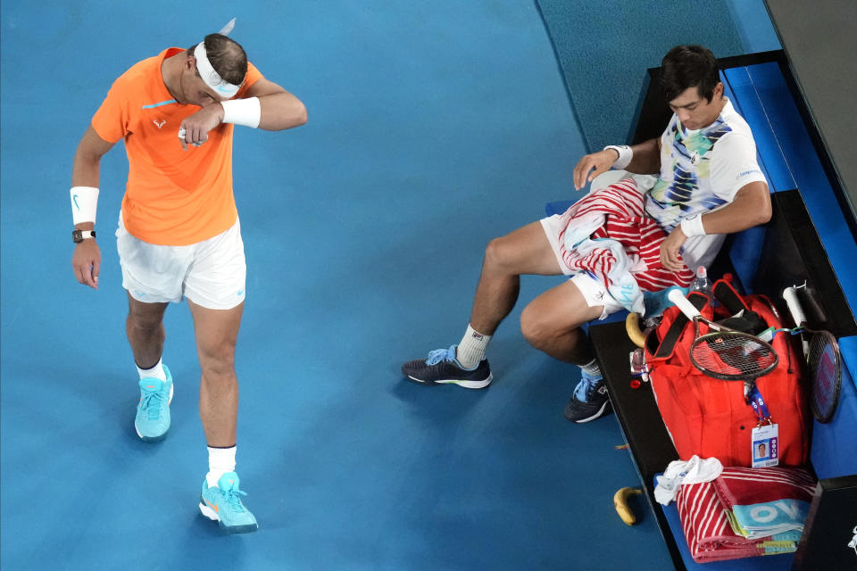 Rafael Nadal, left, of Spain walks past opponent Mackenzie McDonald of the U.S., during a break in their second round match at the Australian Open tennis championship in Melbourne, Australia, Wednesday, Jan. 18, 2023. (AP Photo/Dita Alangkara)