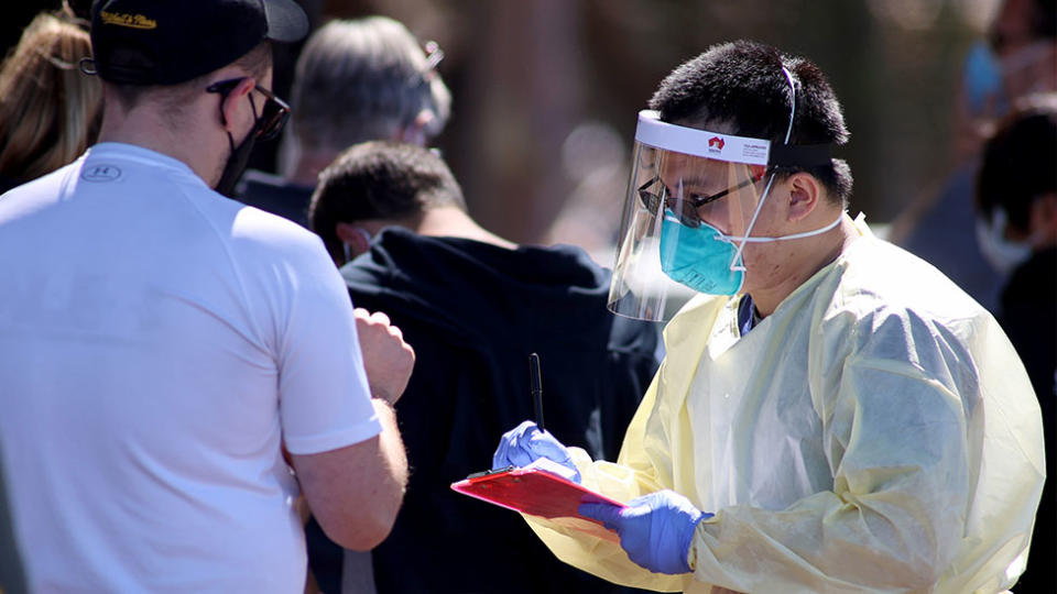 A healthcare worker speaks with a man wearing a mask at a coronavirus testing centre.