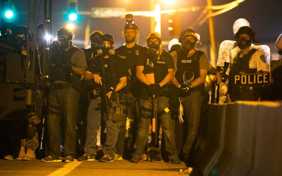 Police officers keep watch while demonstrators protest the death of black teenager Michael Brown in Missouri, in 2014 - REUTERS/Mario Anzuoni 