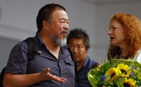 Dissident Chinese artist Ai Weiwei talks with German Green Party member Margarete Bause after he arrived at the airport in Munich, Germany July 30, 2015. REUTERS/Michaela Rehle