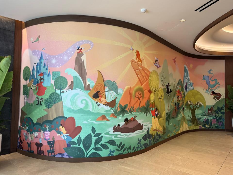 Disneyland mural on curved wall featuring characters like Peter Pan and Moana