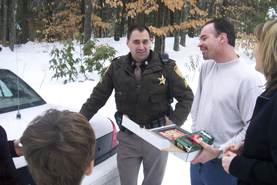 In this Ryan Wasson family photograph, a box of "Santa's Book of Candy," is delivered to Eric Wasson by Carroll County Sheriff's Deputy Tom Riley, center, as a re-gift from Ryan Wasson during Christmas time in 2007, in Wolfeboro, N.H. Two New Hampshire brothers have gotten their holiday regifting skills down to an art, and have been passing the same hard candy treats back and forth for over 30 years. Starting in 1987, Ryan Wasson gave the treat to his brother Eric Wasson as a joke for Christmas, knowing that Eric wouldn't like it. (Ryan Wasson family photograph via AP)