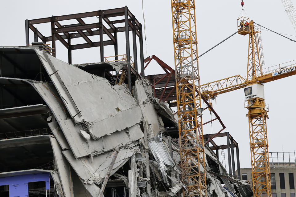 Workers begin the process of preparing the two unstable cranes for implosion at the collapse site of the Hard Rock Hotel, which underwent a partial, major collapse while under construction last Sat., Oct., 12, in New Orleans, Friday, Oct. 18, 2019. Plans have been pushed back a day to bring down two giant, unstable construction cranes in a series of controlled explosions before they can topple onto historic New Orleans buildings, the city's fire chief said Friday, noting the risky work involved in placing explosive on the towers. (AP Photo/Gerald Herbert)